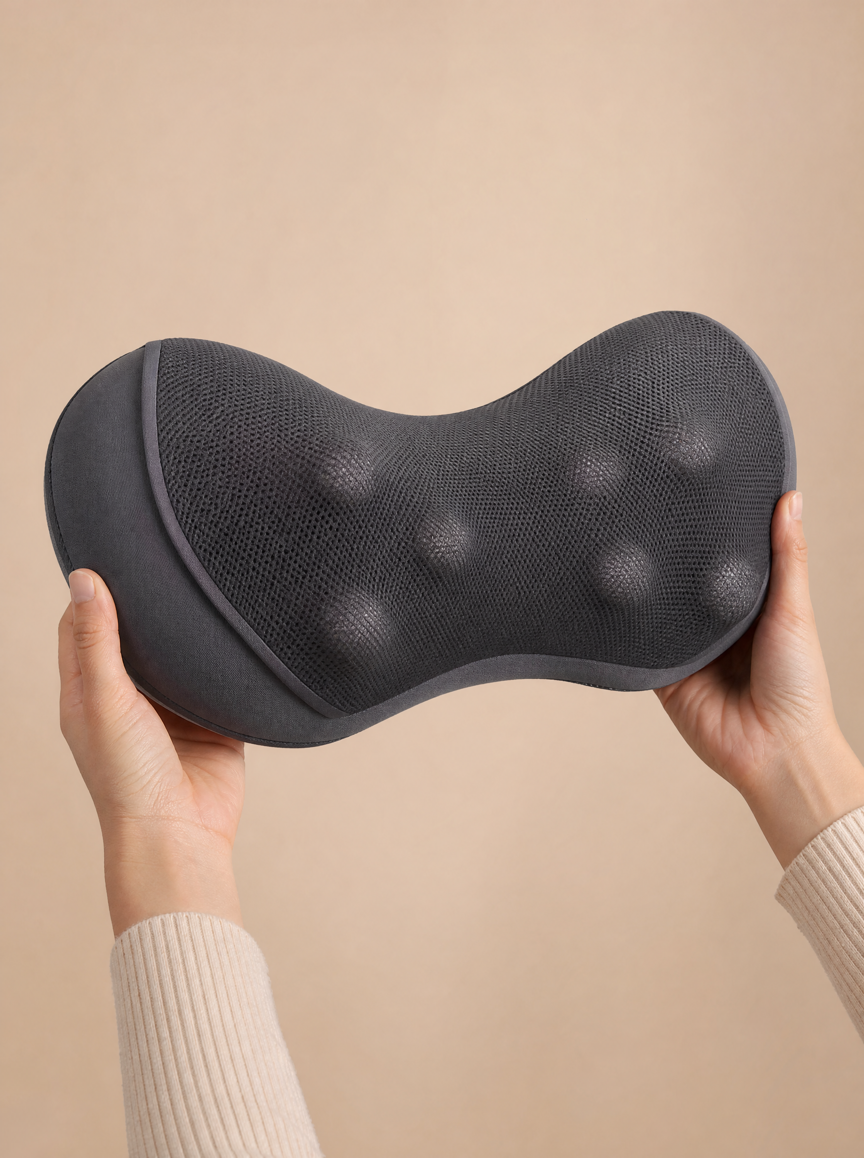 Hands holding the CircuitTech CervicaCloud Pro neck massage pillow showing the contoured shape and bobbled texture for scale
